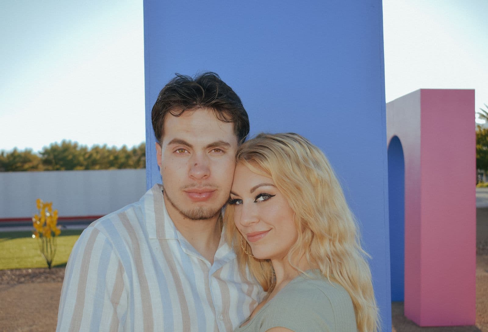 A close portrait of a couple against a blue and pink painted wall in Las Vegas, NV