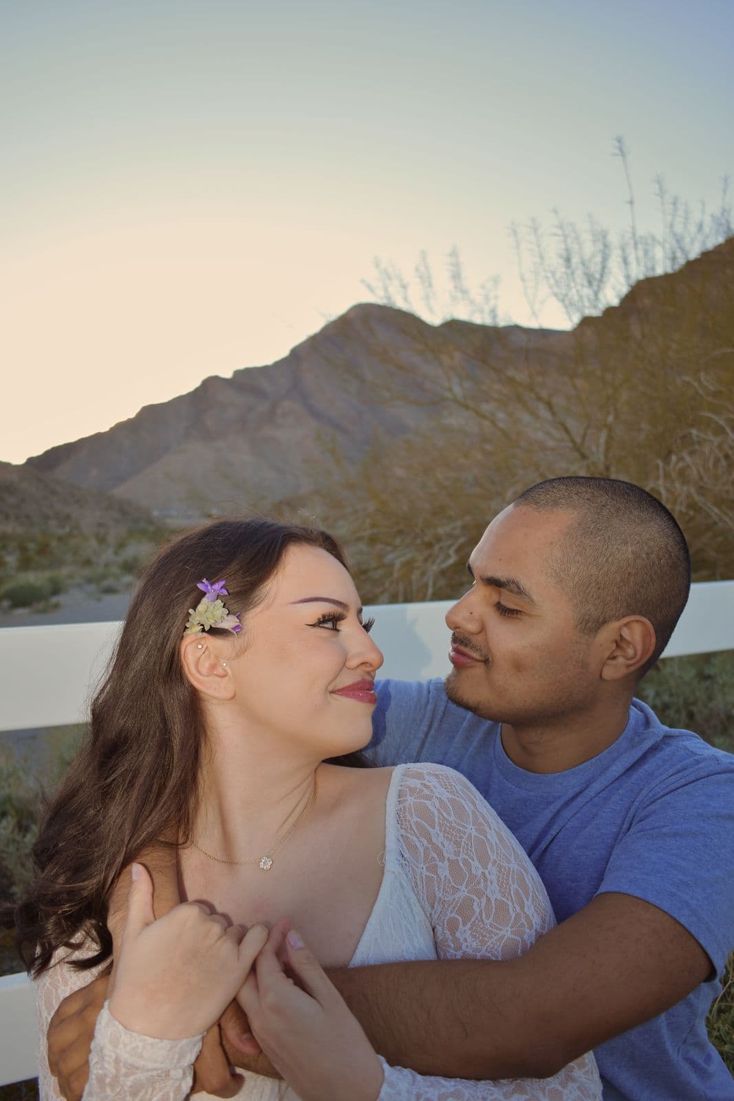 A couple embracing with desert mountains rising behind them near Las Vegas, NV