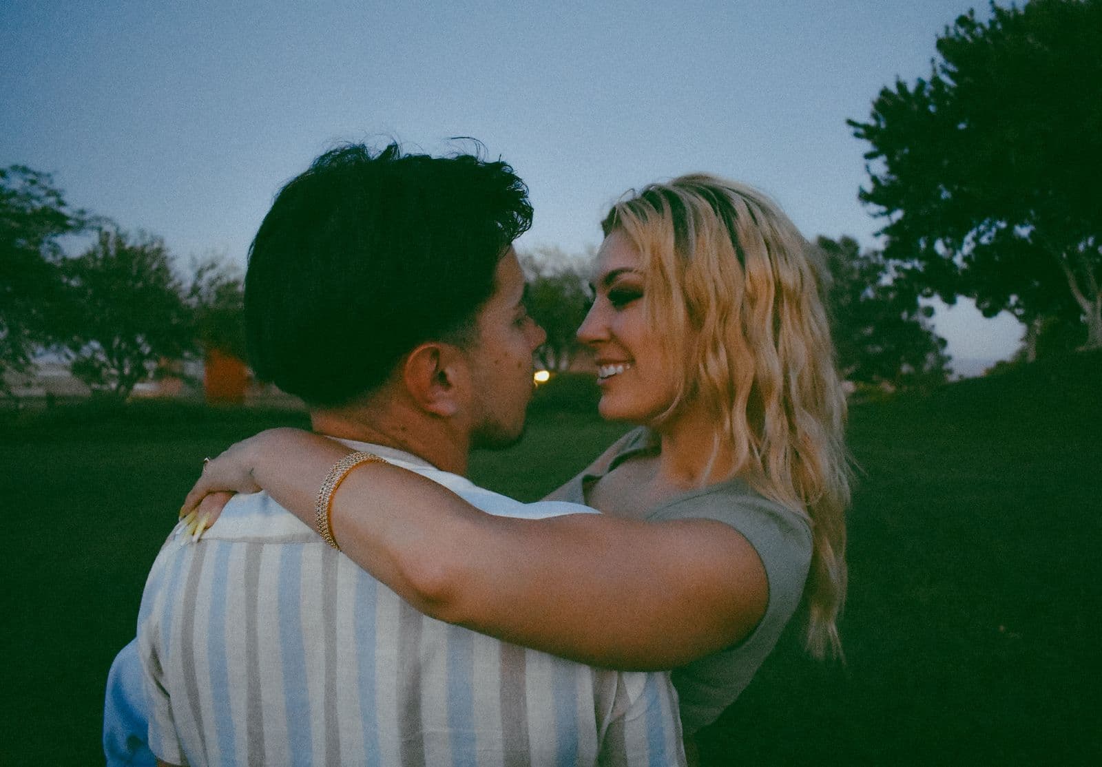 A couple embracing on a wide green lawn during a session in Las Vegas, NV
