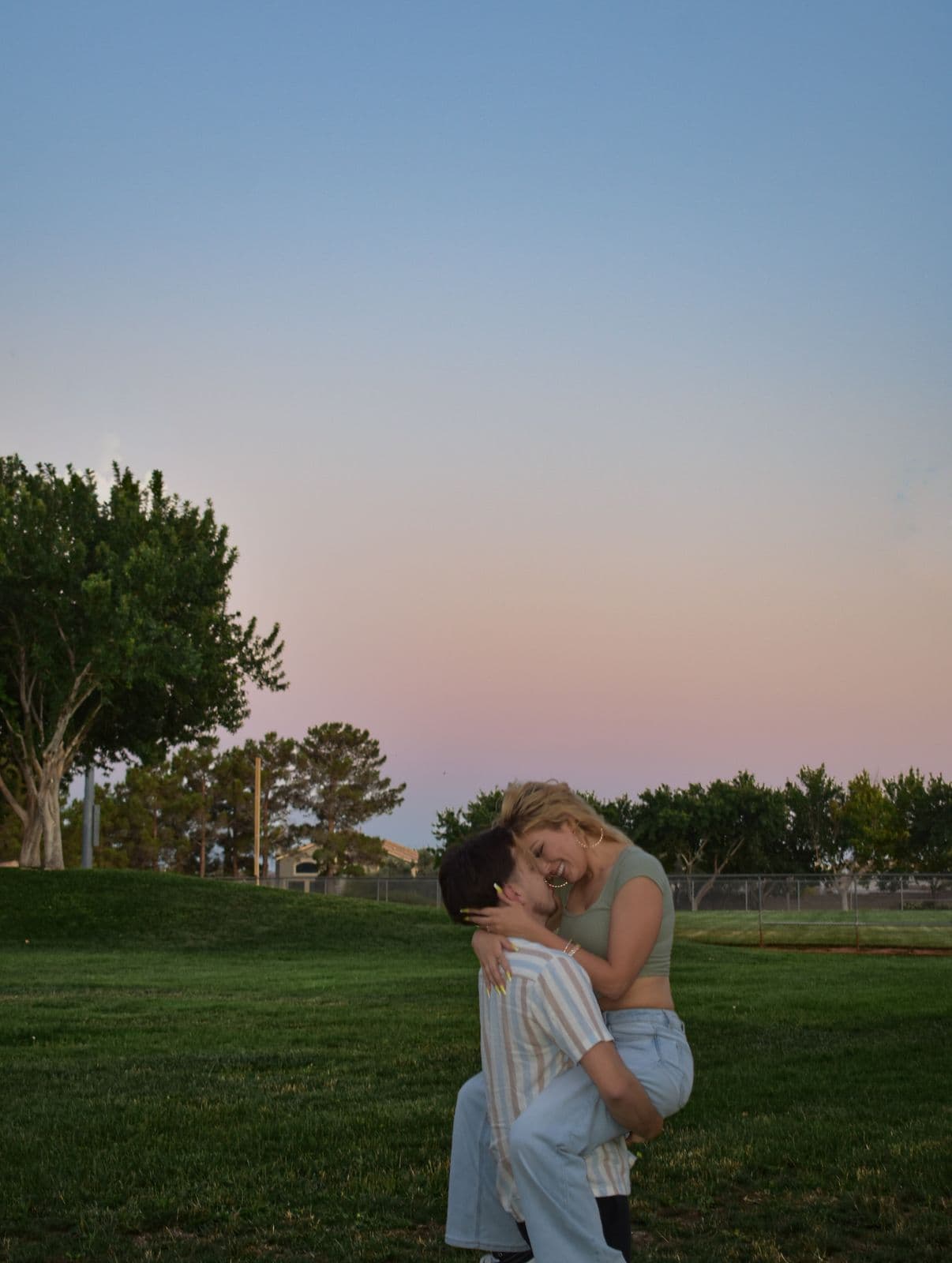 A couple embracing on a lawn as the sky turns pink at sunset in Las Vegas, NV