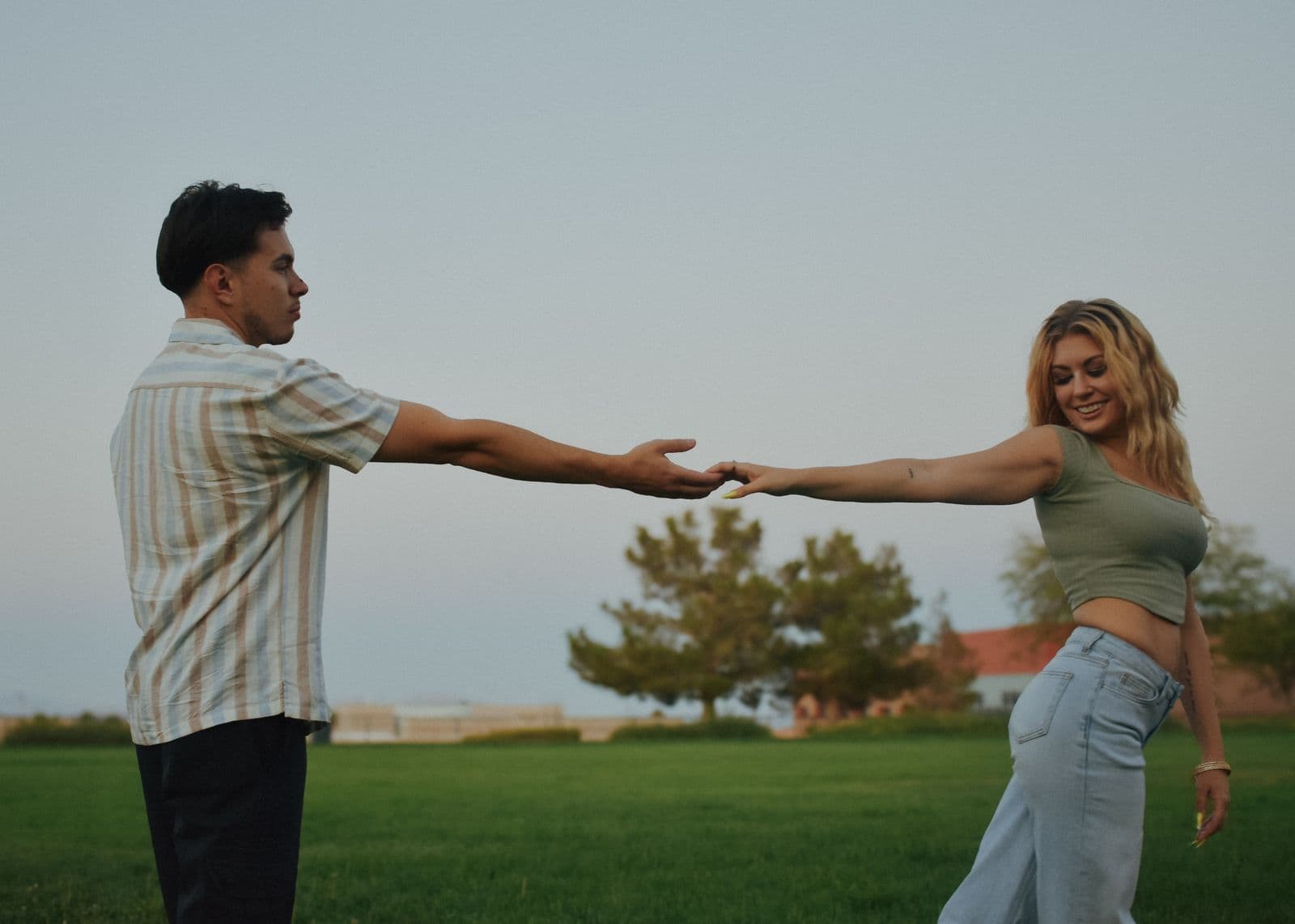A couple holding hands and leaning apart on a park lawn in Las Vegas, NV