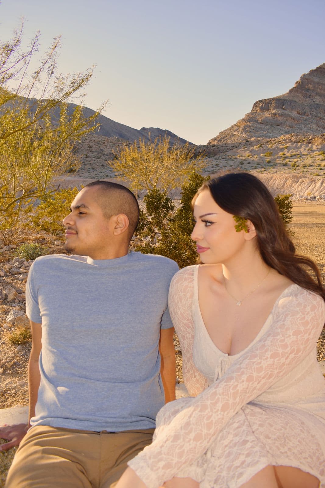 A couple looking at each other among desert brush at golden hour near Las Vegas, NV