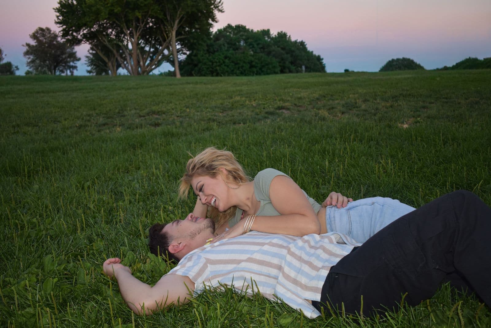 A couple lying on the grass together at dusk during a session in Las Vegas, NV