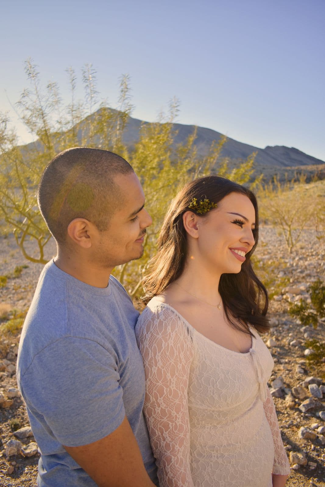 A couple standing close together with a desert mountain behind them near Las Vegas, NV