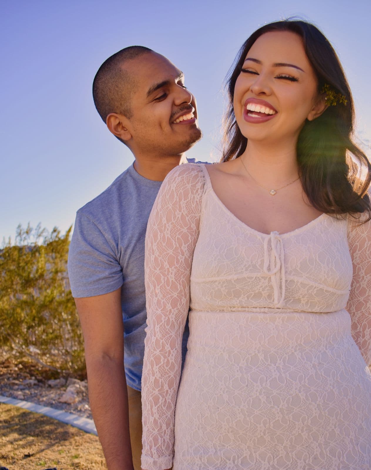 A couple standing together in the desert, she laughs as he smiles beside her, near Las Vegas, NV