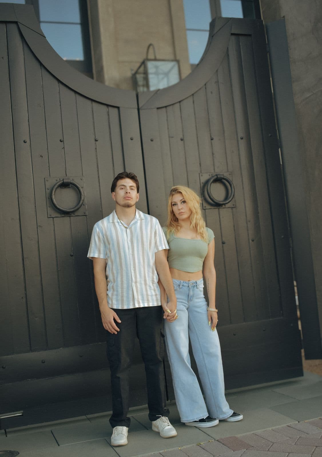 A couple standing before tall wooden gates during a portrait session in Las Vegas, NV