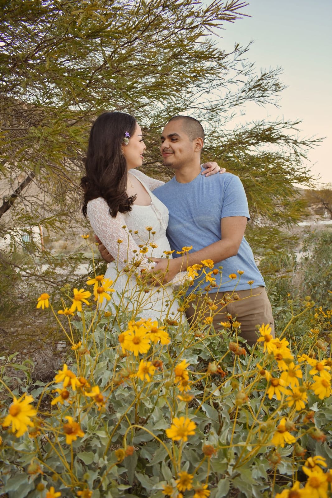 A couple embracing behind a stand of yellow desert wildflowers near Las Vegas, NV