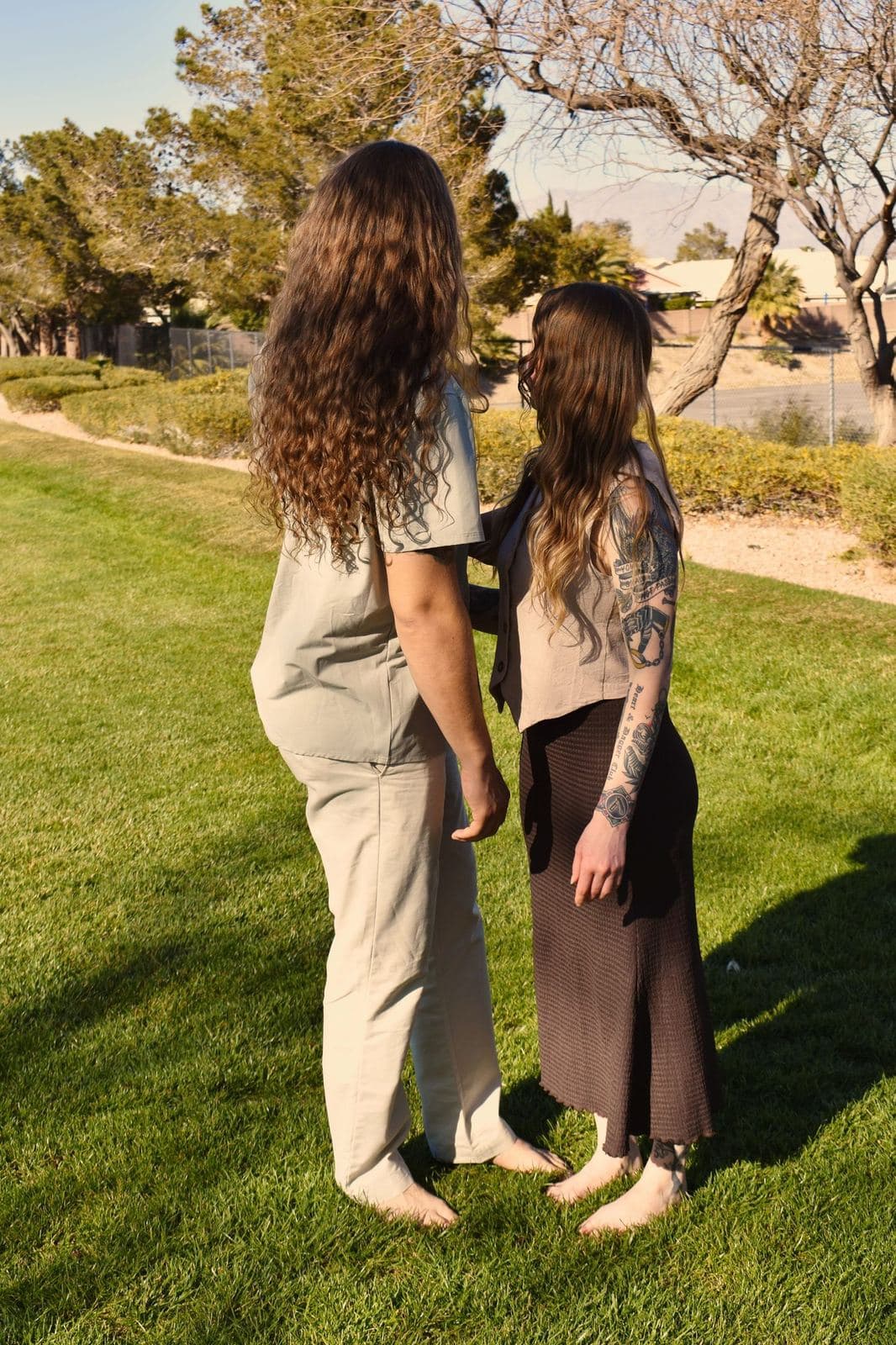 A couple standing barefoot facing each other on a park lawn at golden hour in Las Vegas, NV