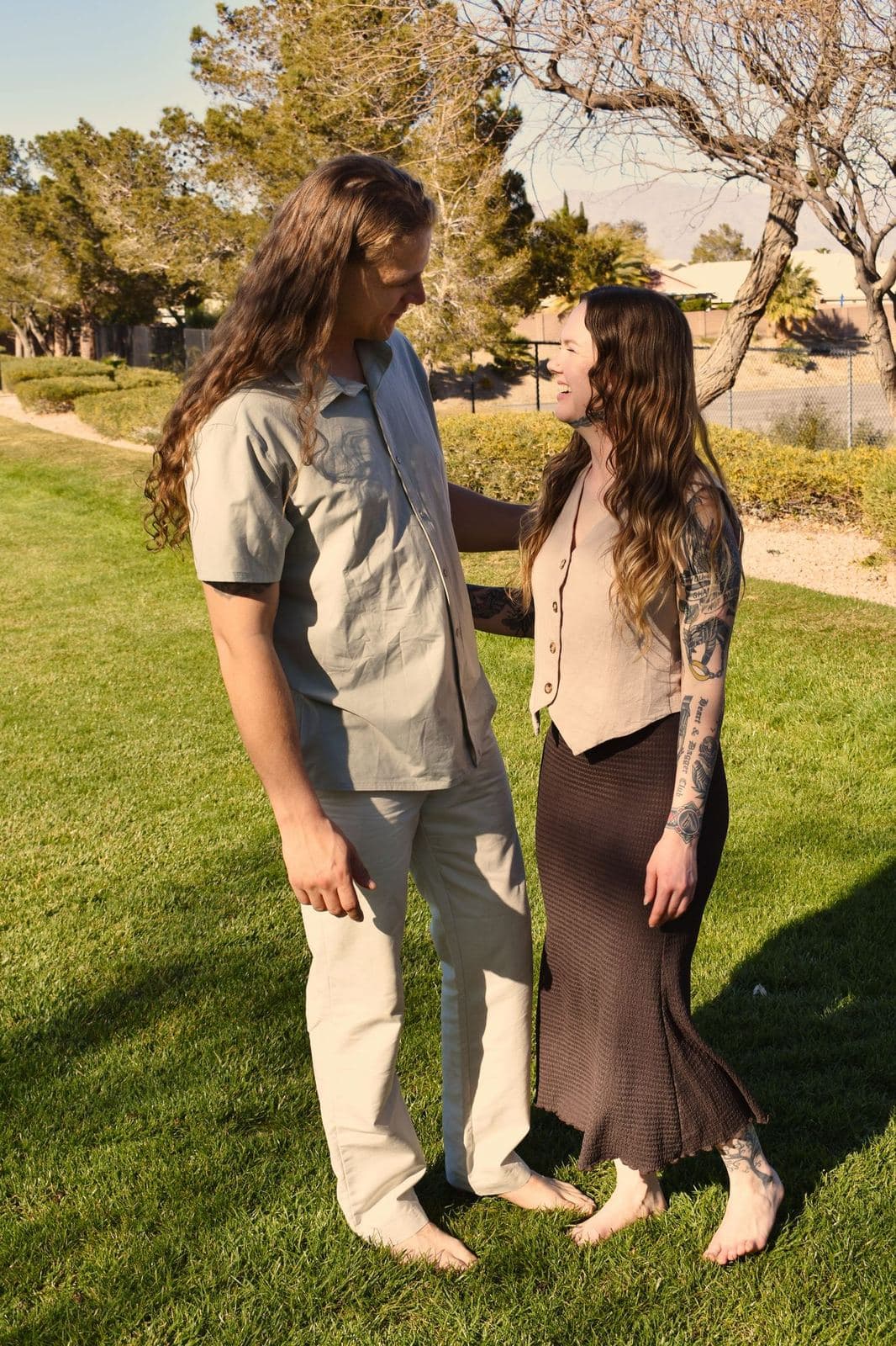 A couple holding hands and looking at each other on a park lawn in Las Vegas, NV