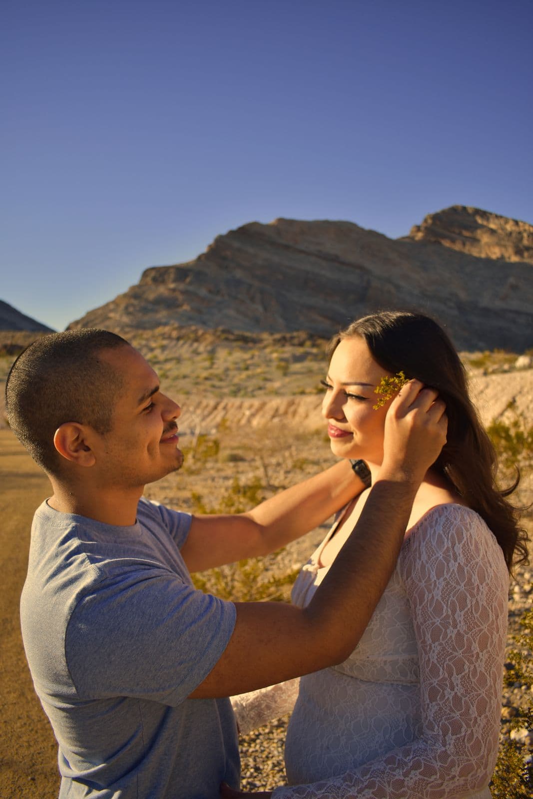 A man brushing his partner's hair back from her face as they both smile, near Las Vegas, NV