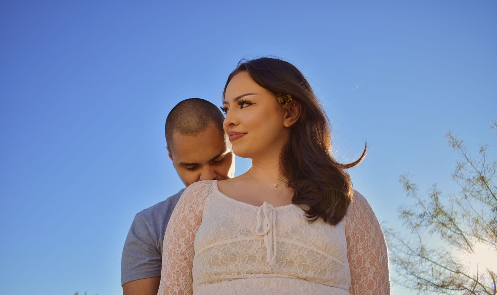 A man resting his head on his partner's shoulder against a clear blue sky near Las Vegas, NV