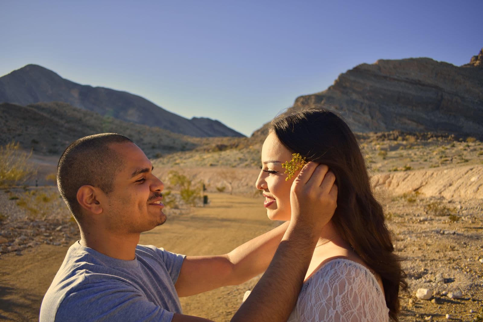 A man cupping his partner's face as they look at each other in the desert near Las Vegas, NV