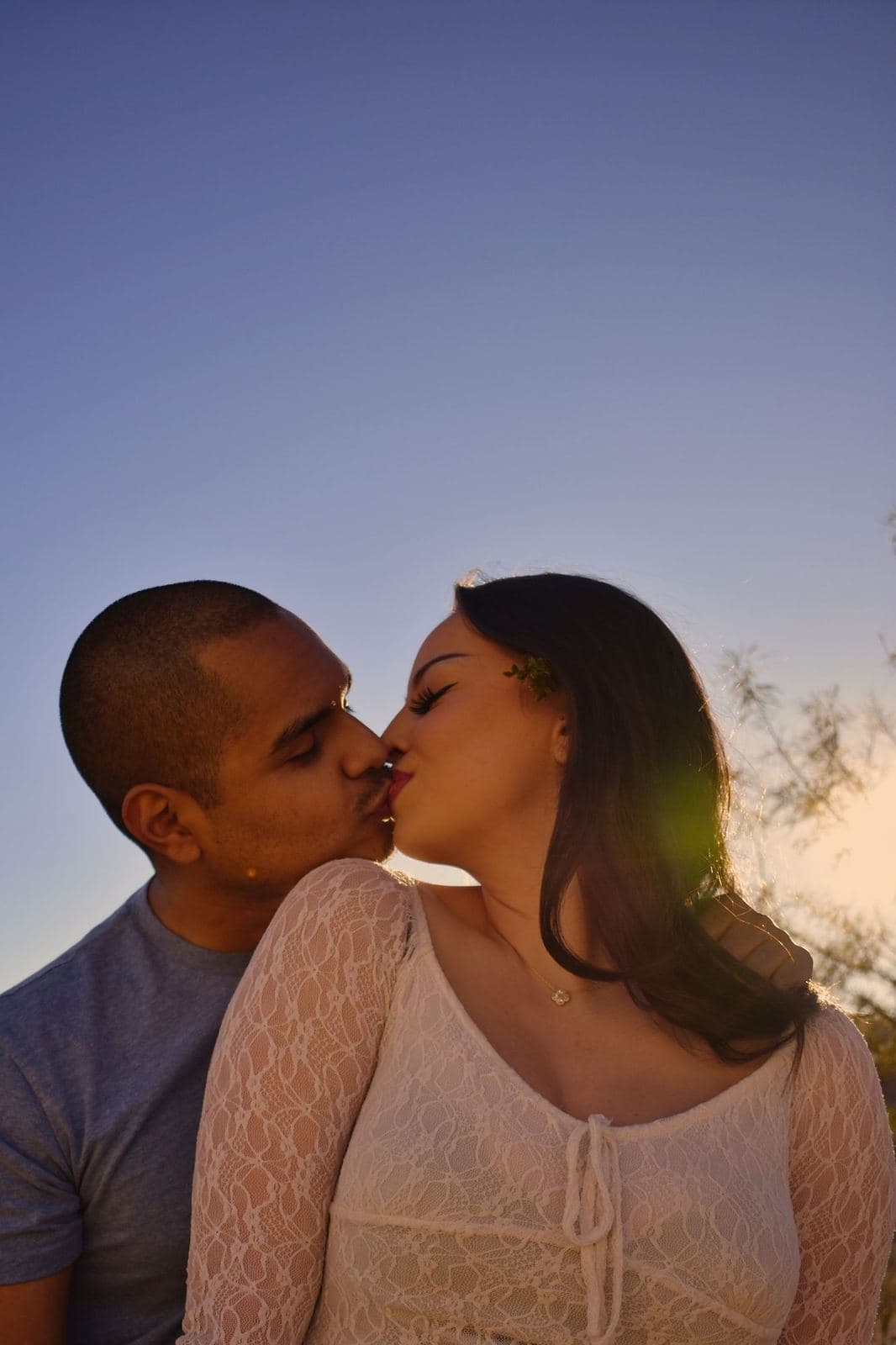 A couple kissing at sunset with the low sun flaring behind them near Las Vegas, NV