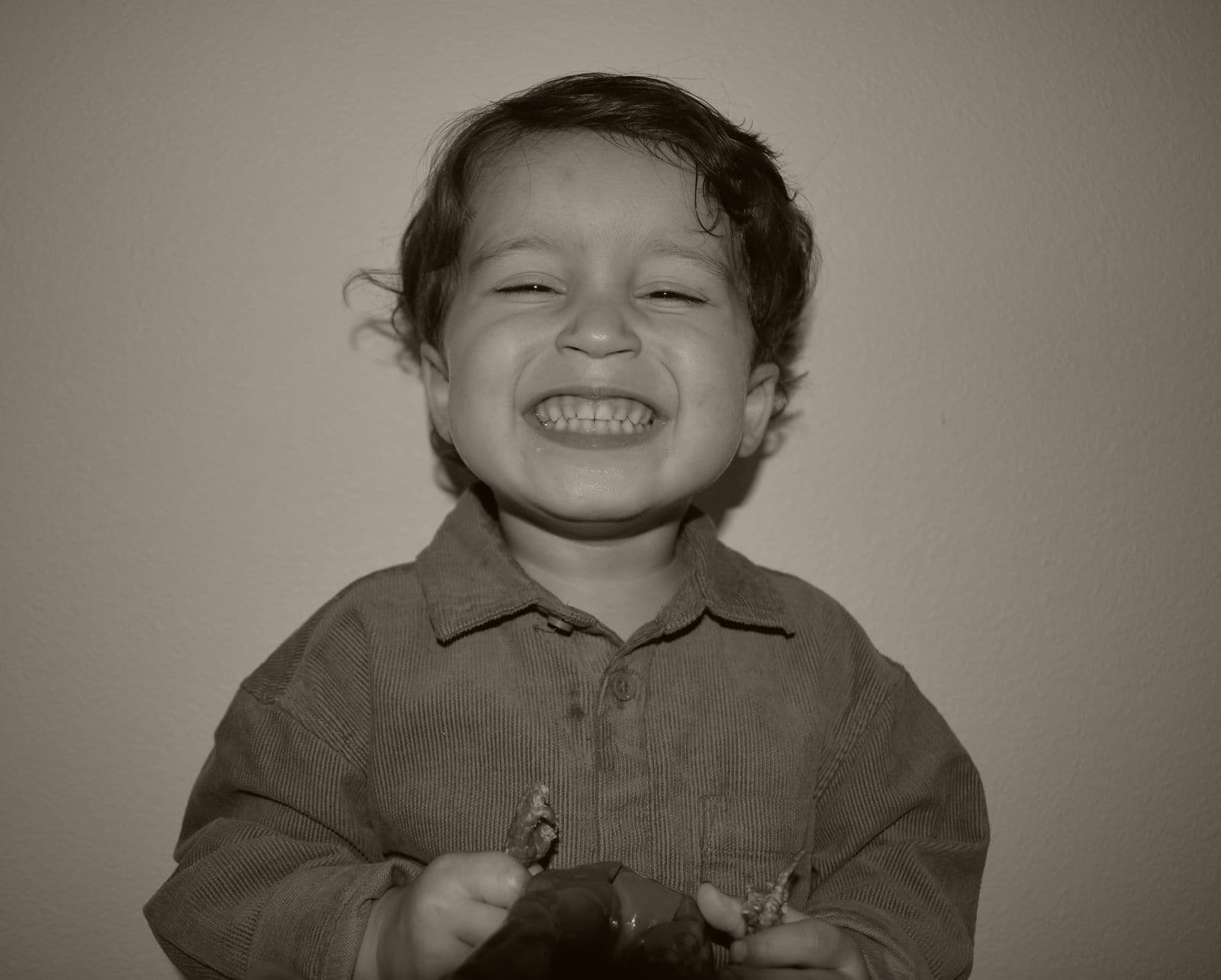 A black-and-white frame of a laughing young boy during an at-home family session in Las Vegas, NV