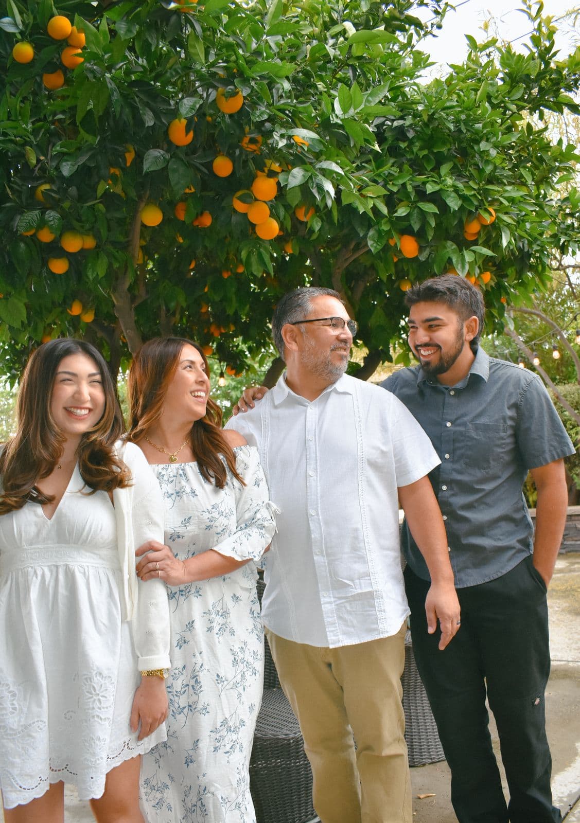 An extended family of five standing together among orange trees during a family session in Las Vegas, NV