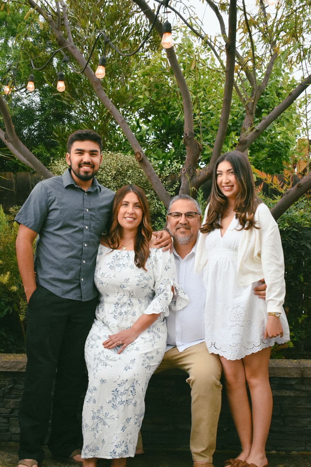 A family of five gathered along a garden wall under string lights in Las Vegas, NV