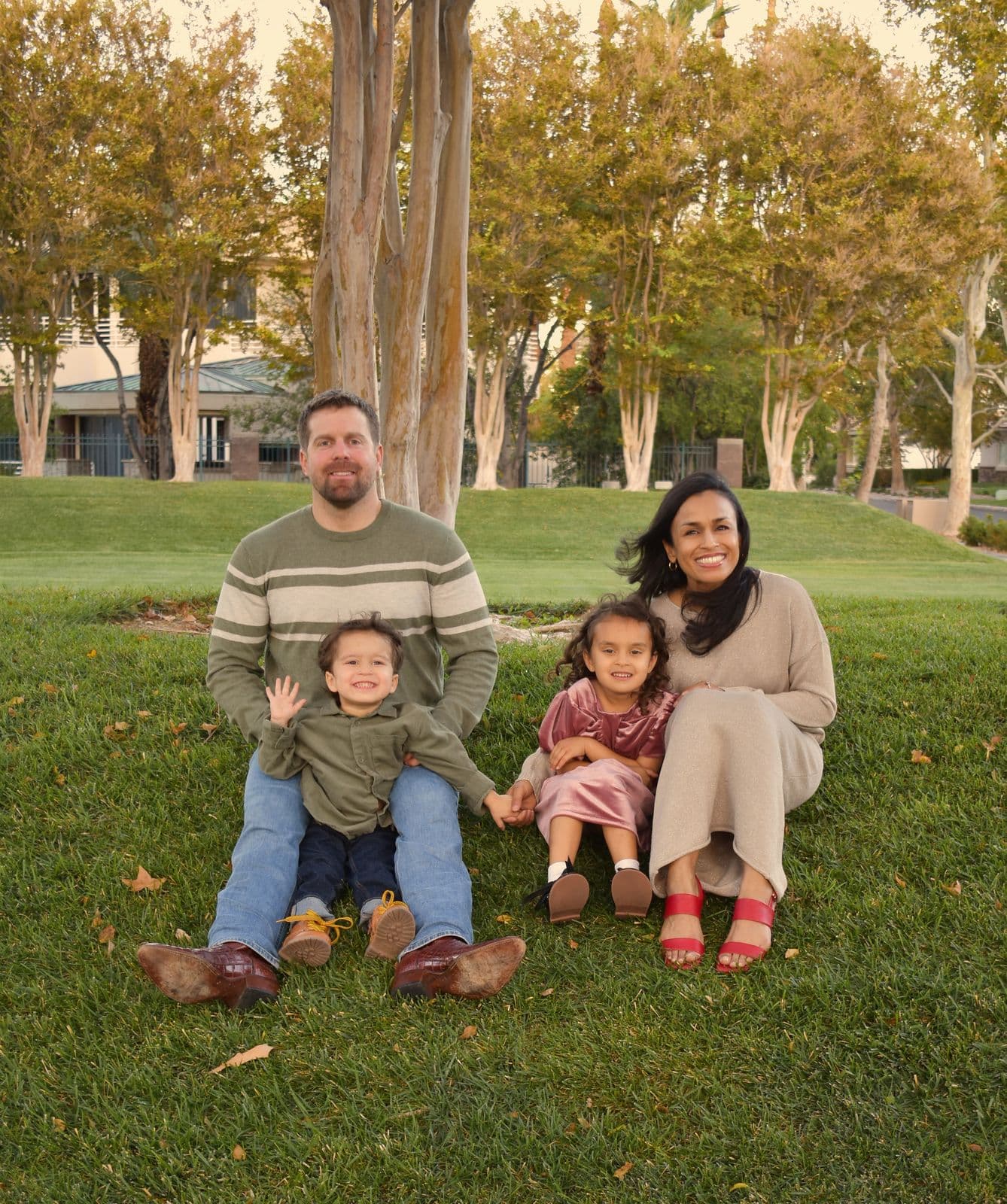 A family of four seated together on a lawn at golden hour during a Las Vegas, NV family session