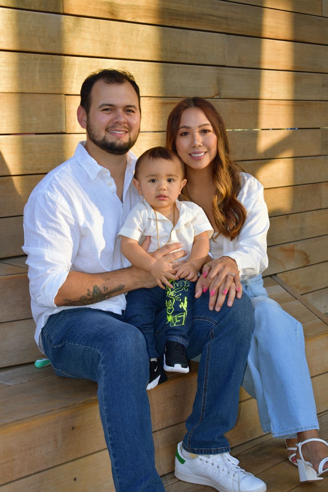 A family of three seated together against a wooden wall during a session in Las Vegas, NV