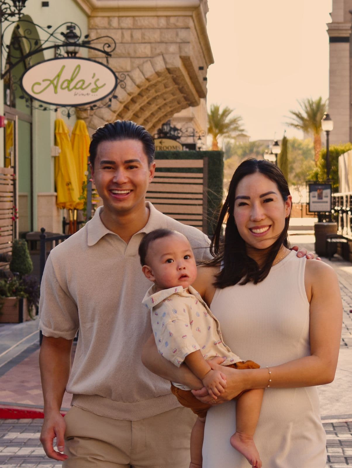 A family of three standing in front of a storefront during an evening session in Las Vegas, NV