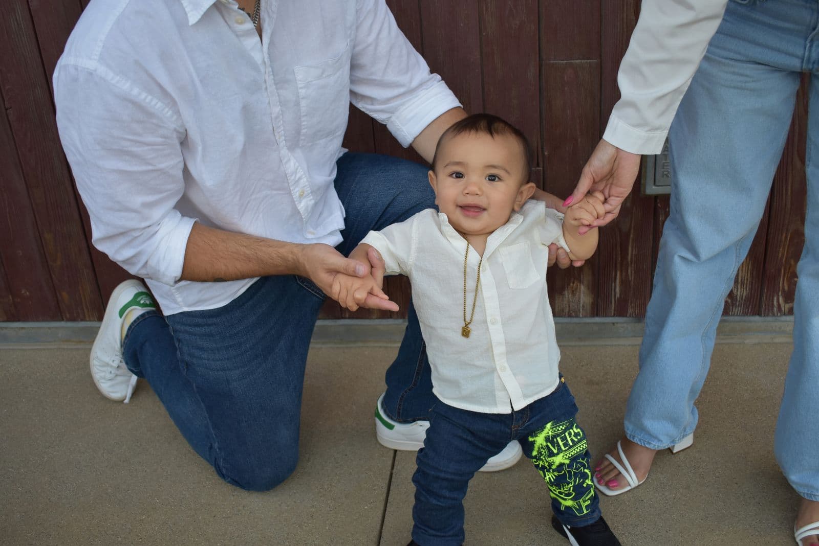 A father crouching to hold his toddler's hands as he takes steps, Las Vegas, NV family session