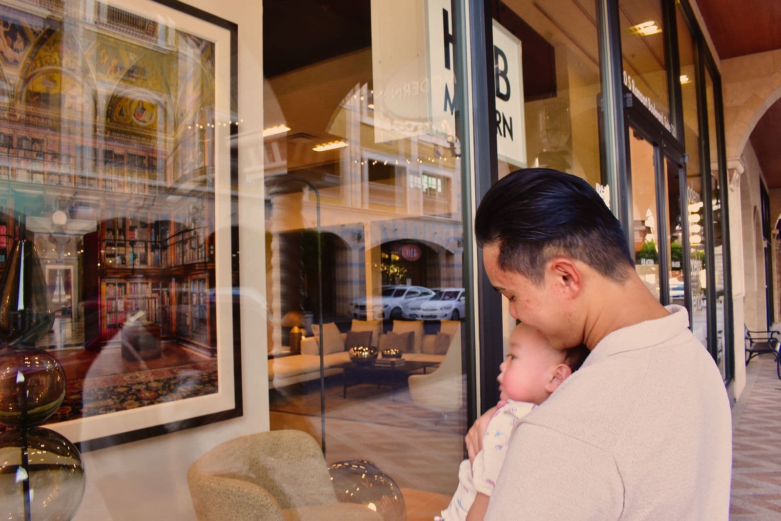 A father holding his baby beside a lit storefront during an evening family session in Las Vegas, NV