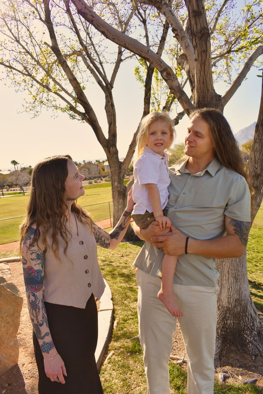 A father holding his toddler while her mother reaches for her hand, Las Vegas, NV family session
