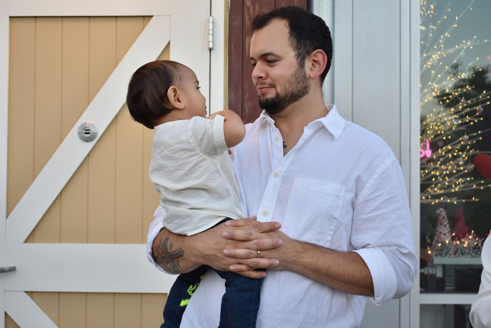 A father holding his toddler son beside a white barn door during a Las Vegas, NV family session