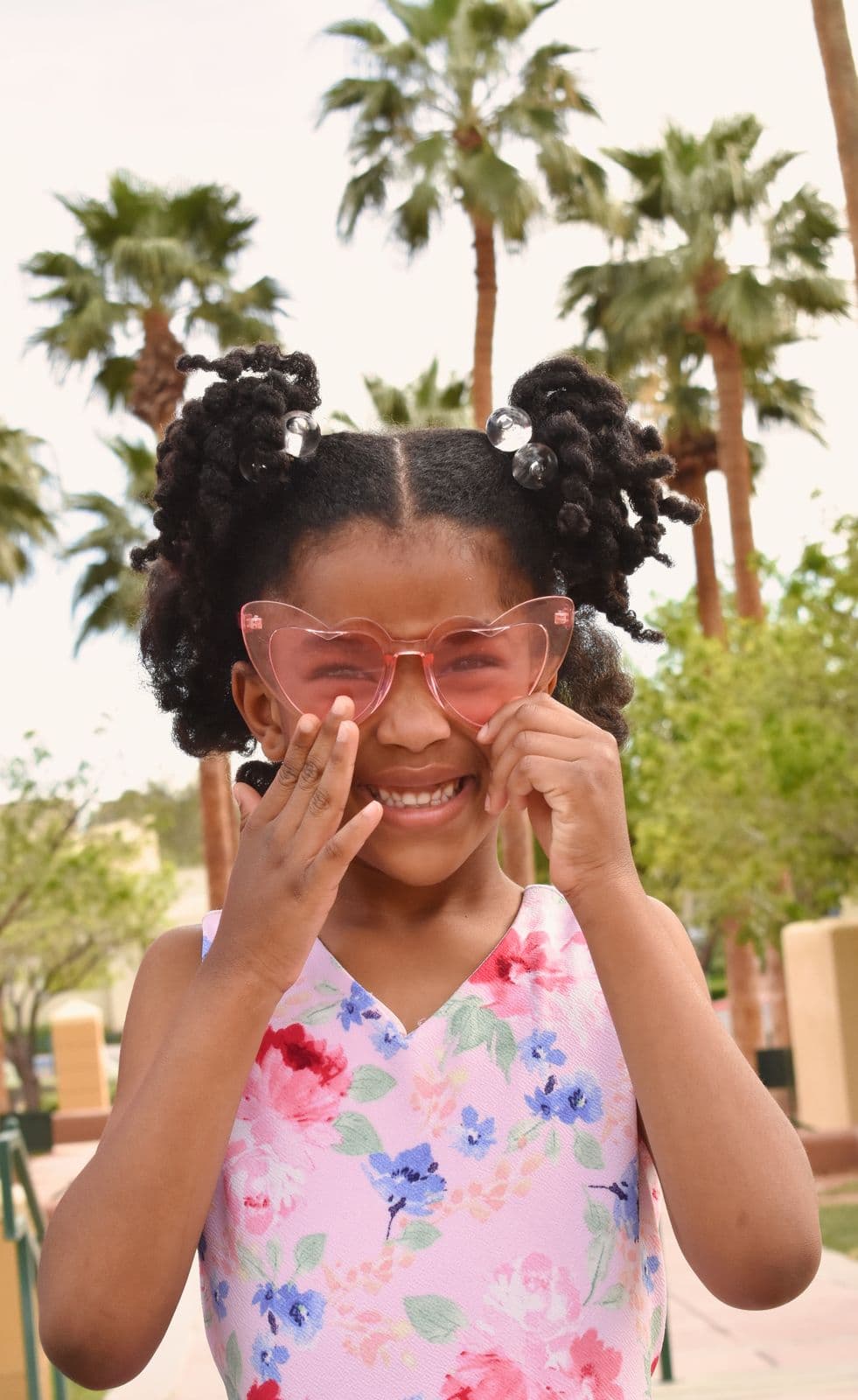 A young girl in pink sunglasses framing her face with both hands, Las Vegas, NV family session