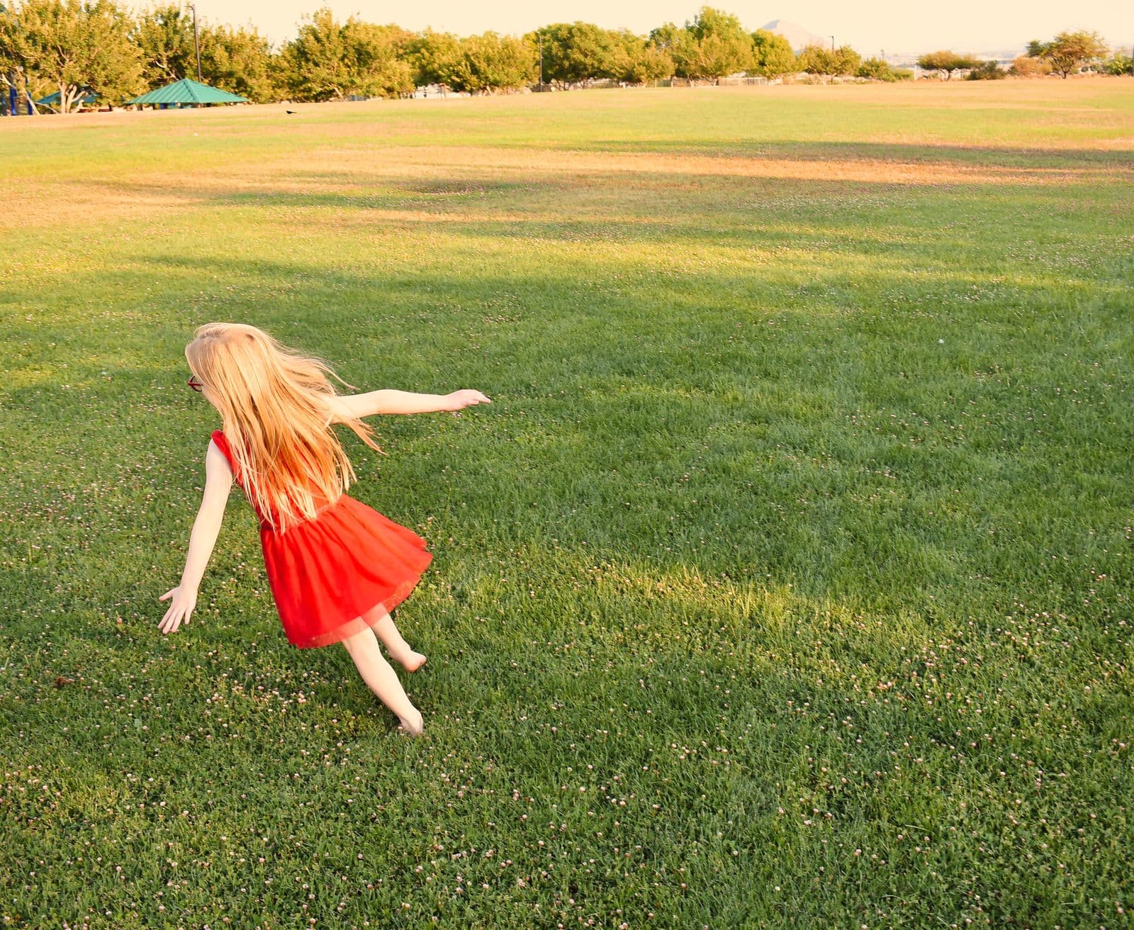 A girl in a red dress running across an open lawn during a family session in Las Vegas, NV