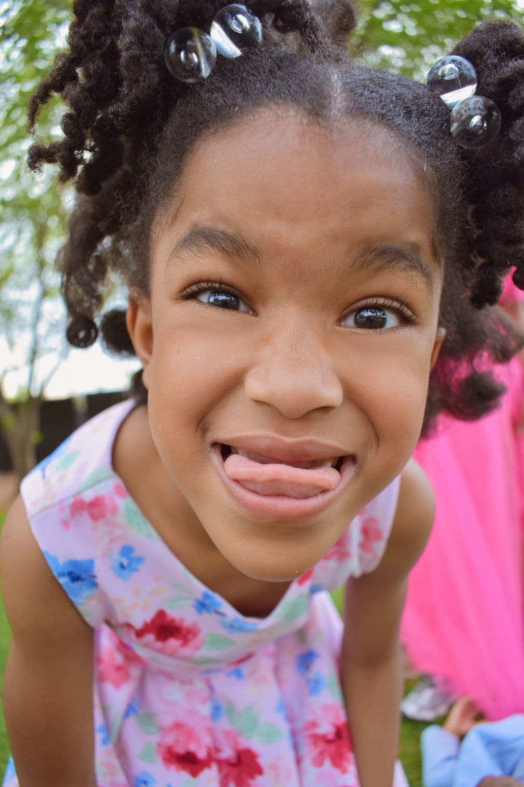 A young girl in a floral dress pulling a silly face during a family photo session in Las Vegas, NV