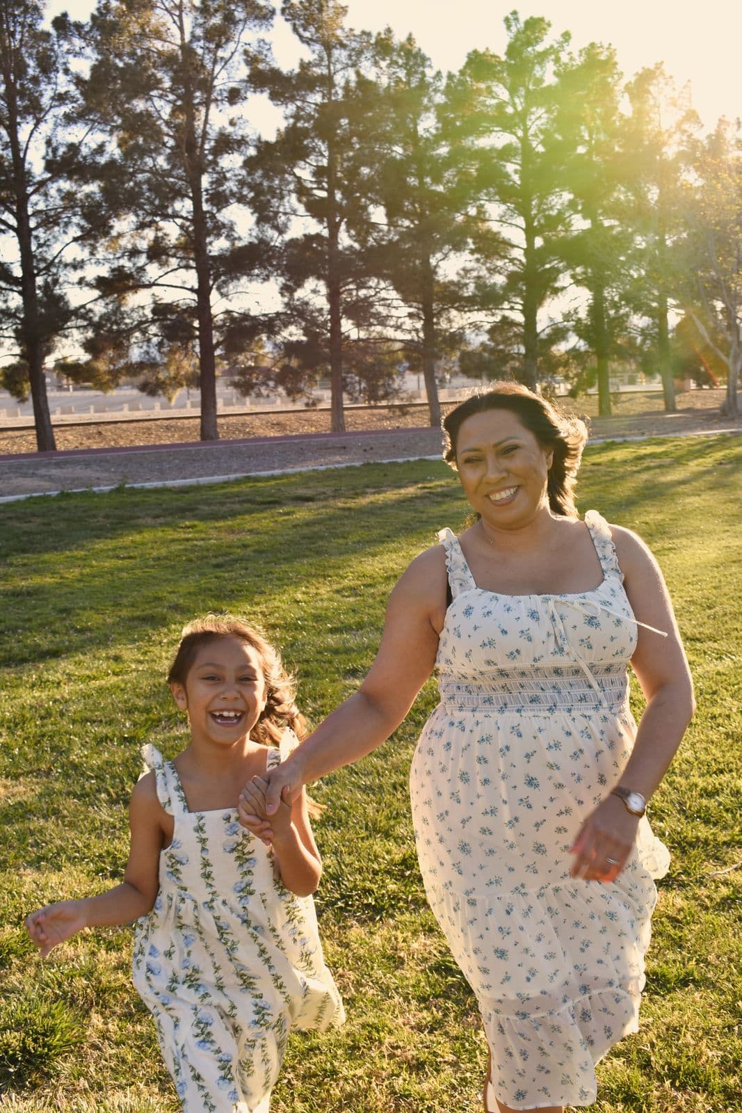 A mother and daughter running together across a backlit lawn during a Las Vegas, NV family session