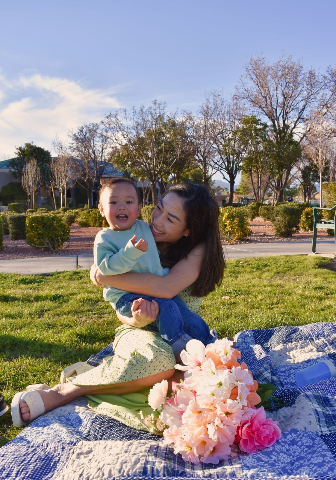 A mother lifting her laughing toddler above a picnic blanket strewn with peonies, Las Vegas, NV