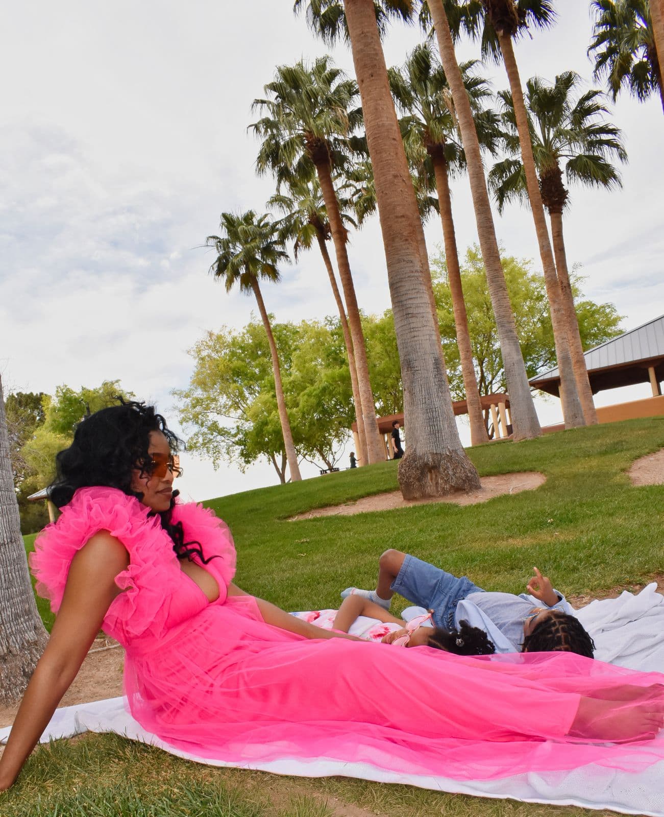 A mother in a pink tulle gown reclining on the grass while her children rest behind her, Las Vegas, NV