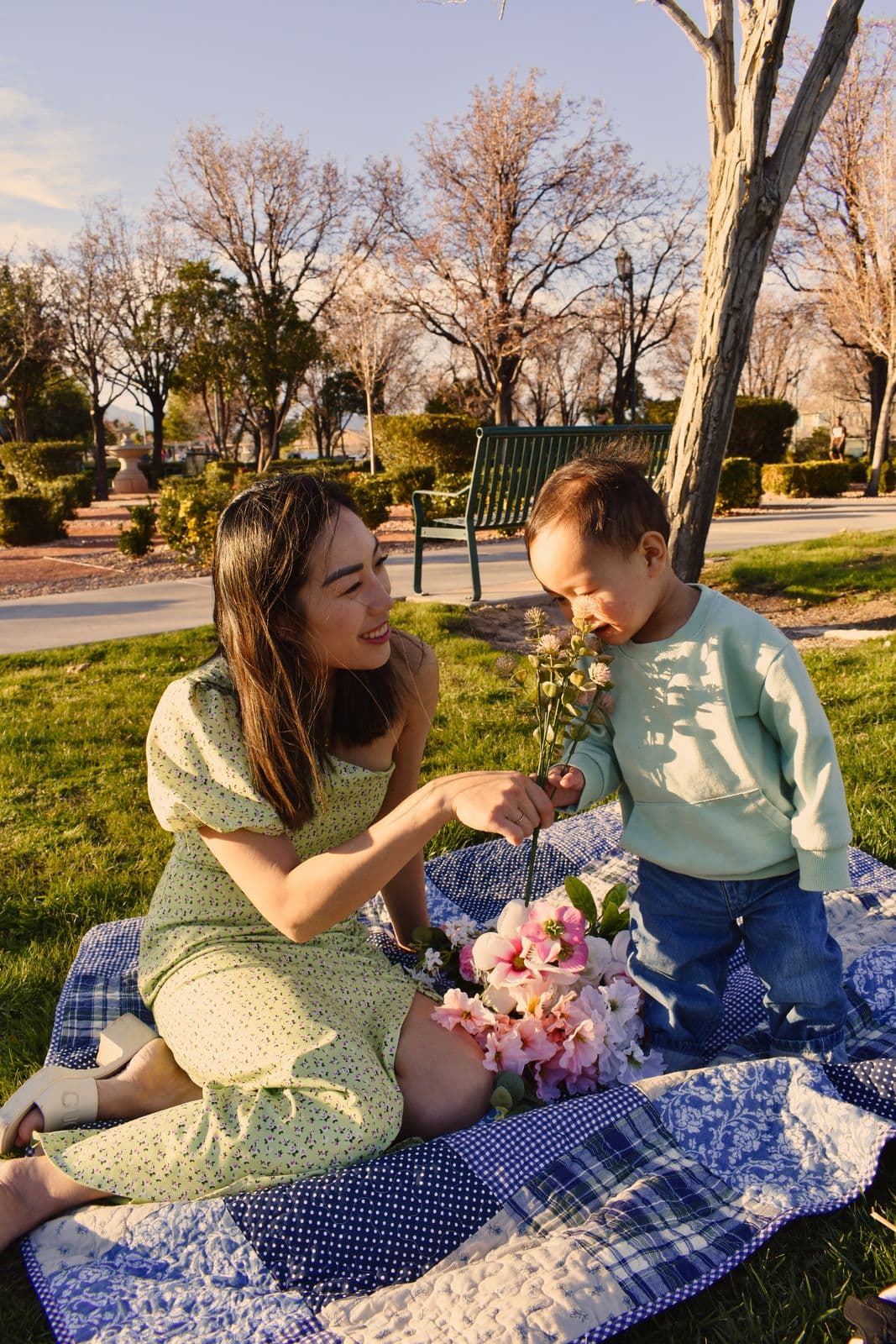 A mother holding a peony up for her toddler son to smell on a picnic blanket in Las Vegas, NV