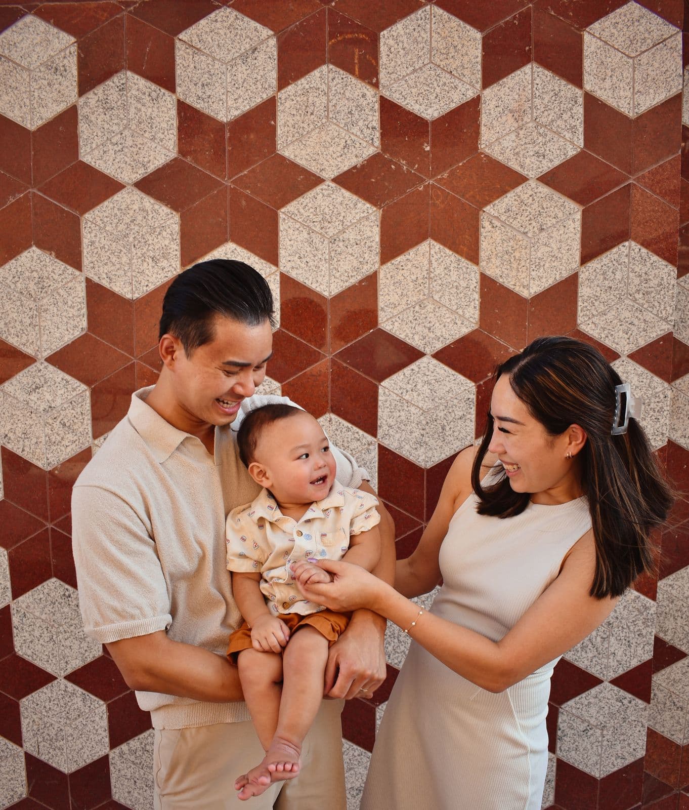 Parents holding their baby between them against a patterned tile wall in Las Vegas, NV