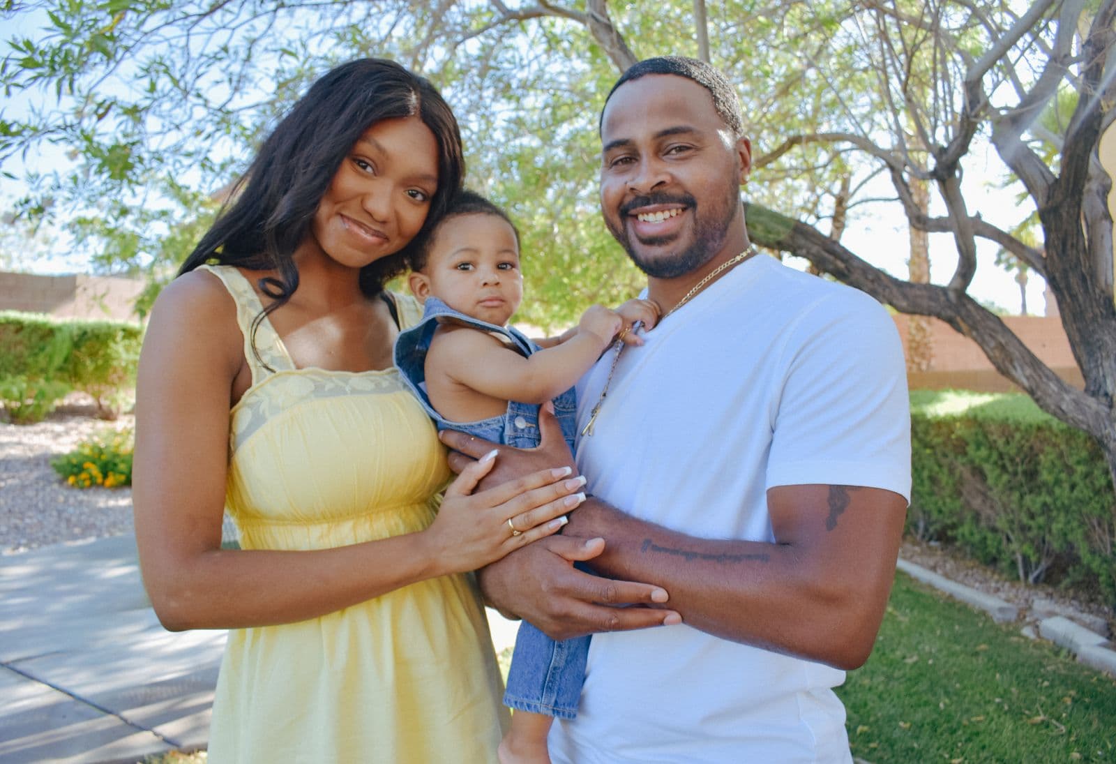 Parents carrying their toddler along a shaded path during an outdoor family session in Las Vegas, NV