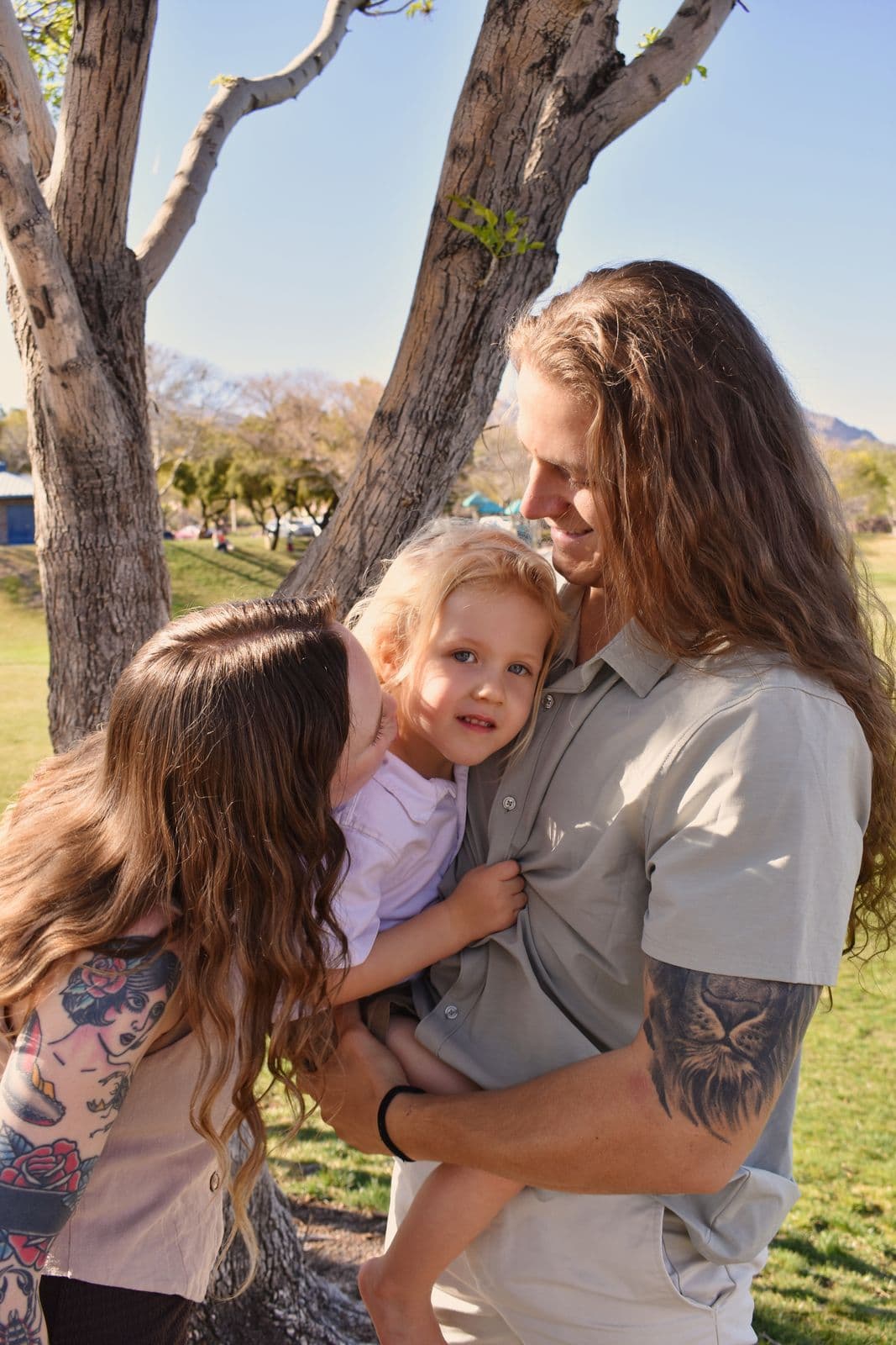 Parents holding their toddler between them under park trees during a Las Vegas, NV family session
