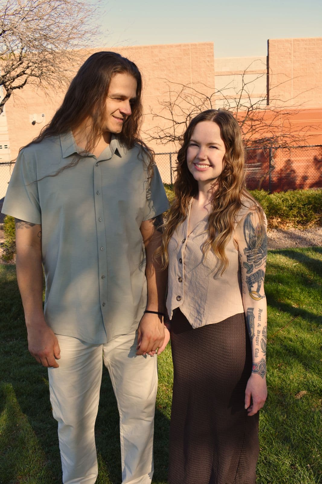 Parents standing together on the grass with a brick building behind them, Las Vegas, NV family session