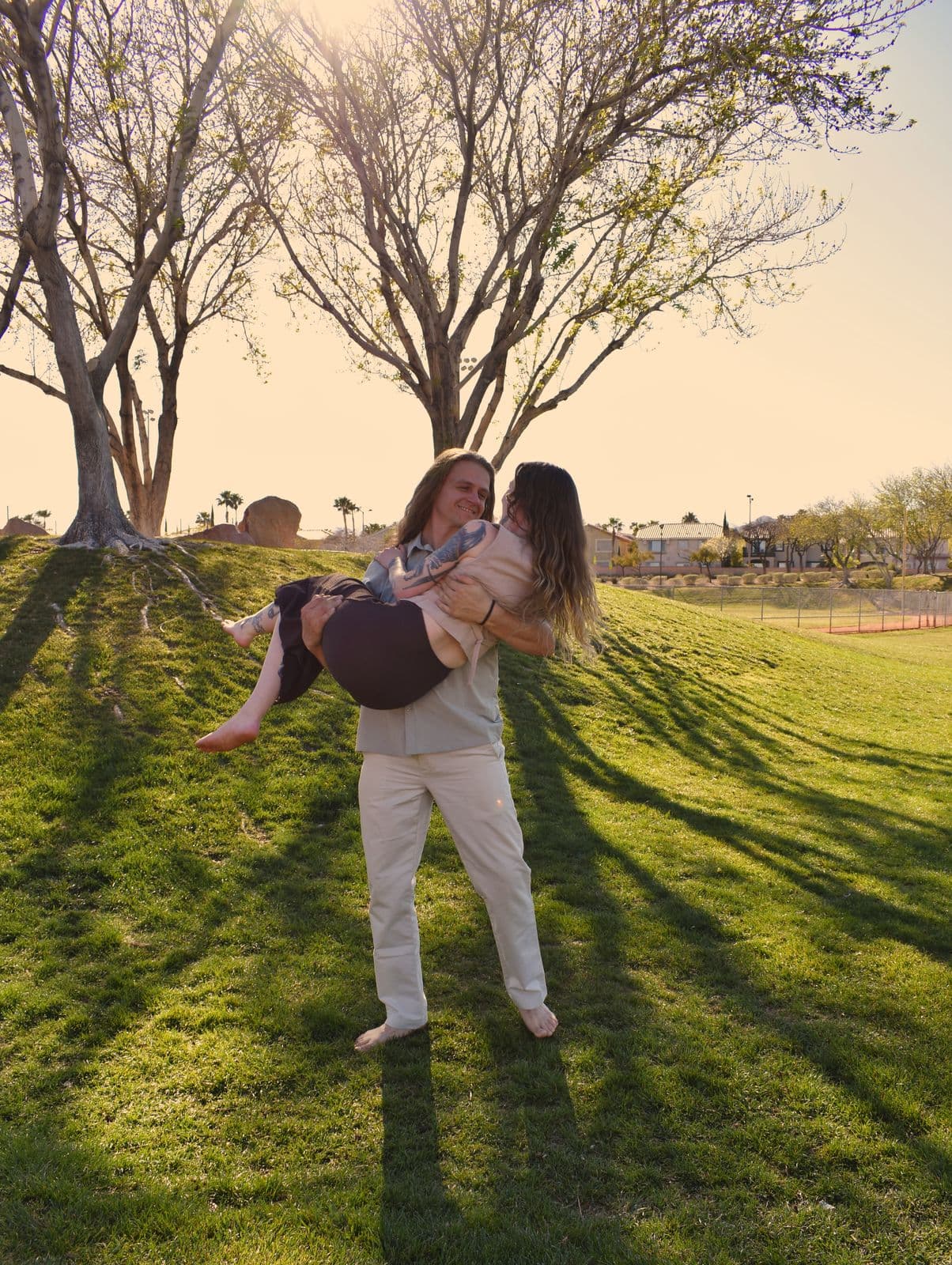 Parents holding their toddler on a lawn with long golden-hour shadows, Las Vegas, NV