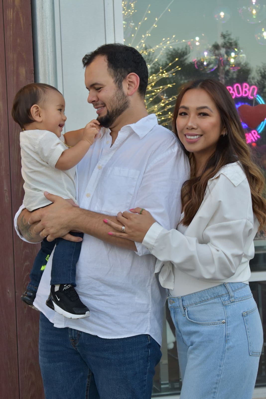 Parents holding their toddler in white shirts and denim outside a storefront in Las Vegas, NV