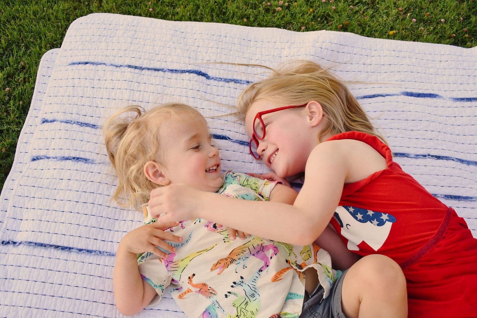Two siblings hugging as they lie together on a striped blanket in Las Vegas, NV