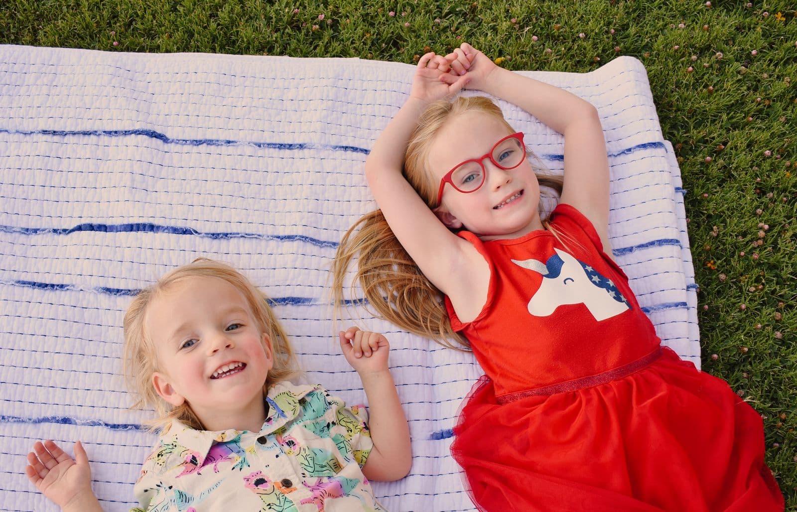 Two young siblings laughing side by side on a picnic blanket during a Las Vegas, NV session