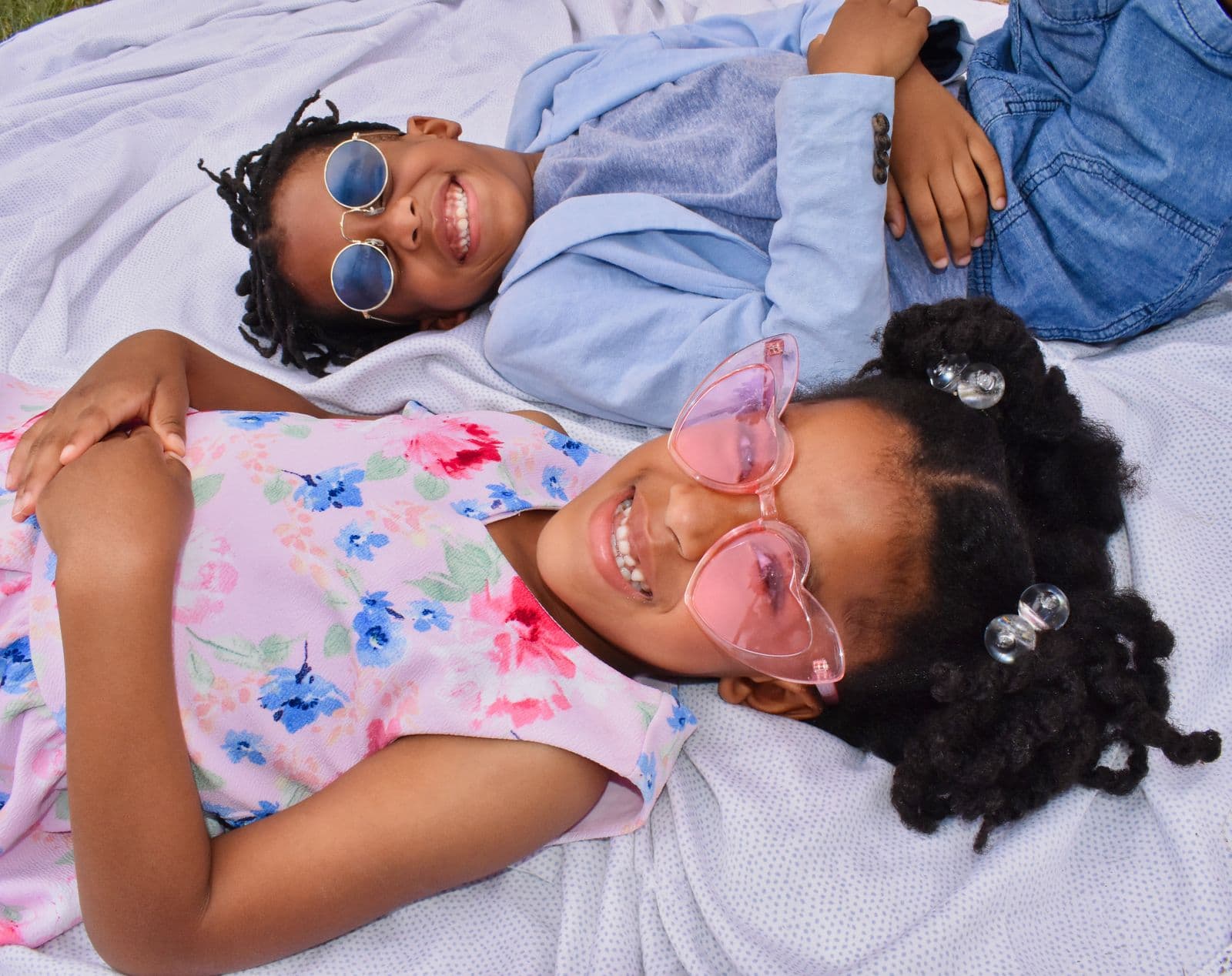 Two siblings in sunglasses lying side by side on a blanket during a Las Vegas, NV family session