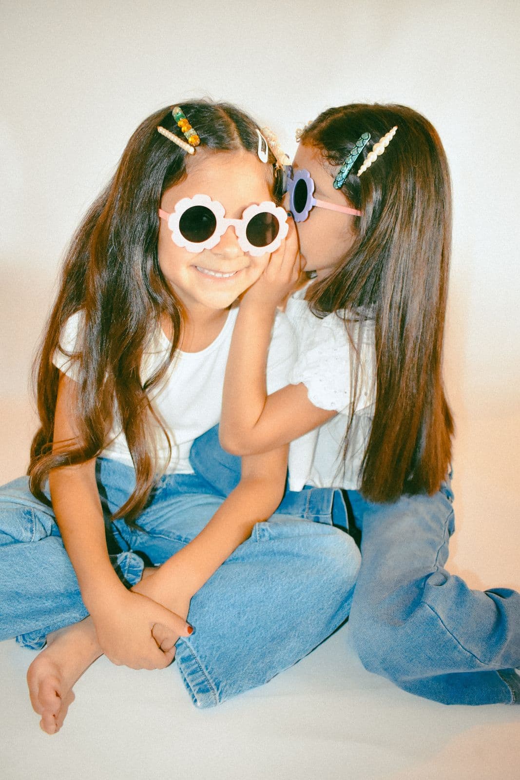 One sister kissing the other's cheek during a studio sibling session in Las Vegas, NV