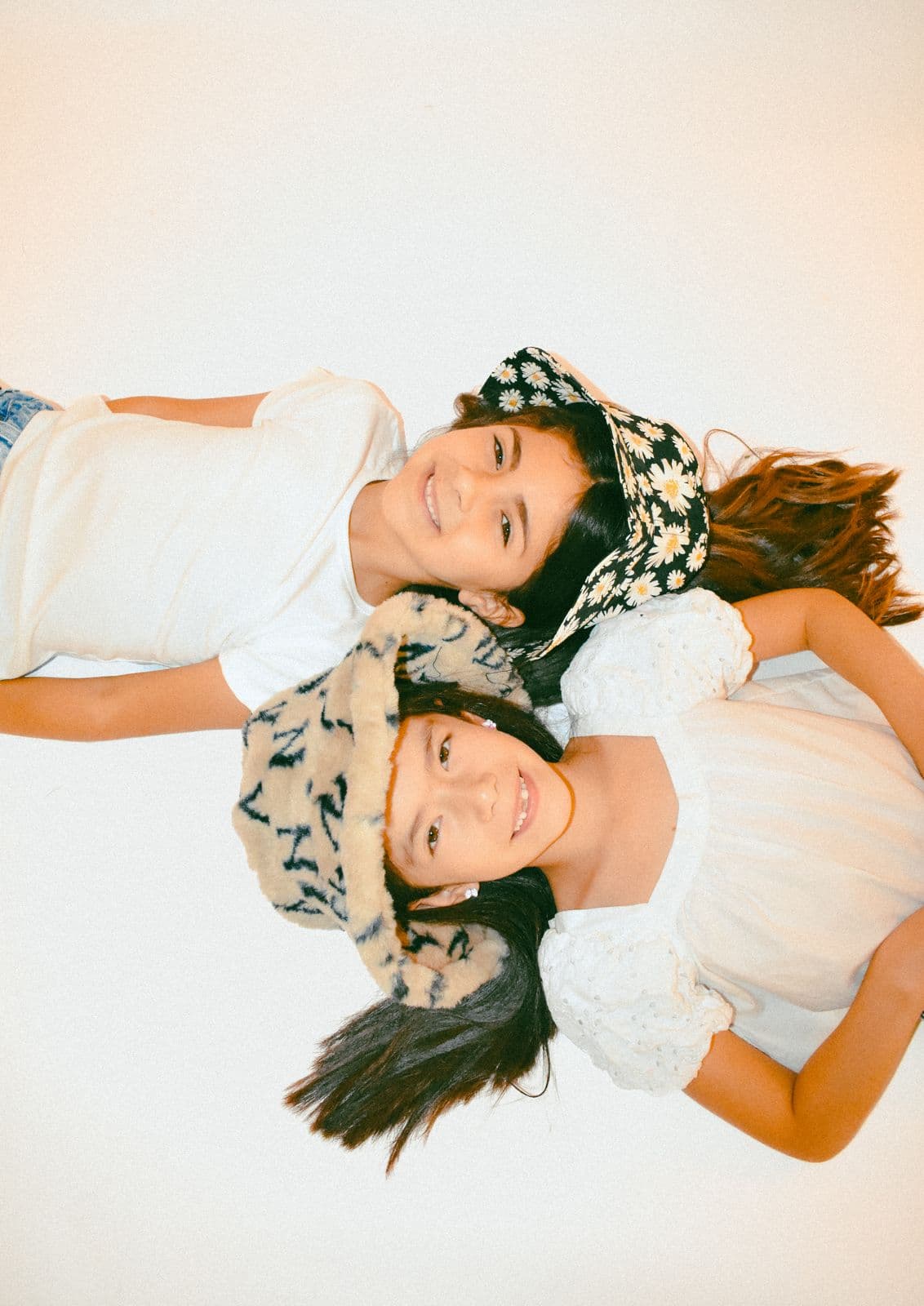 Two sisters in printed bandanas lying head to head on a studio floor in Las Vegas, NV