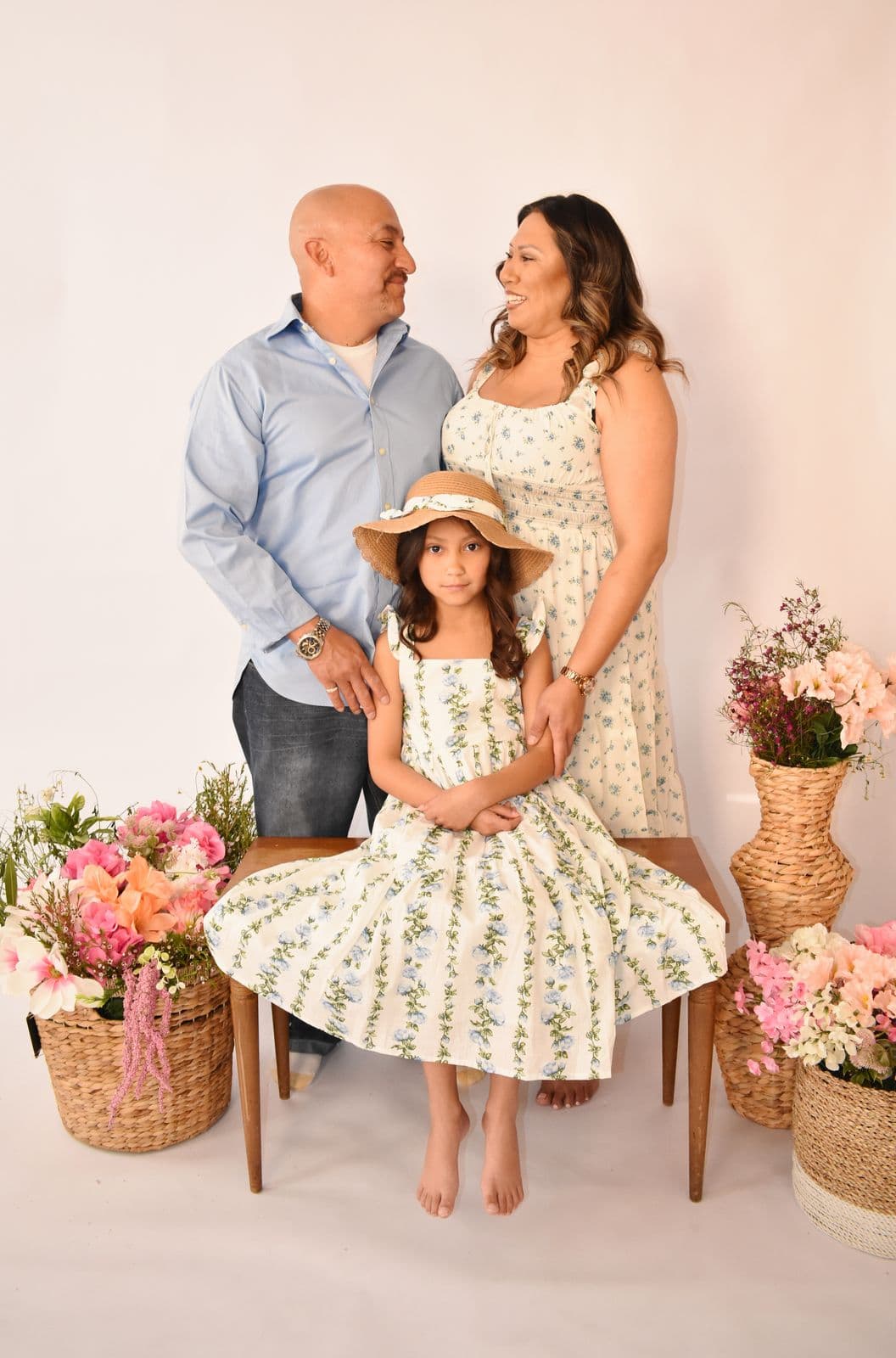 A family of three photographed in studio with flower baskets, their daughter seated in a straw hat, Las Vegas, NV
