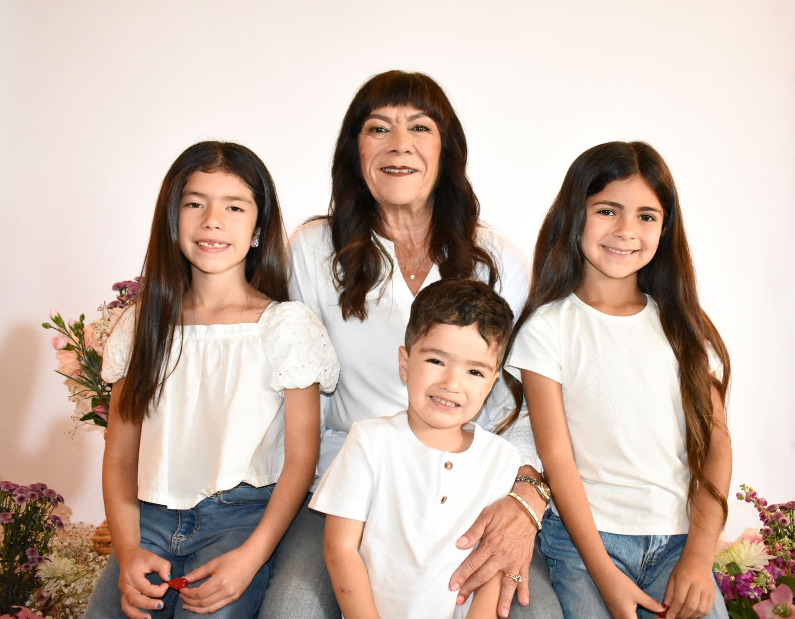 A grandmother photographed in studio with her four grandchildren and baskets of flowers, Las Vegas, NV