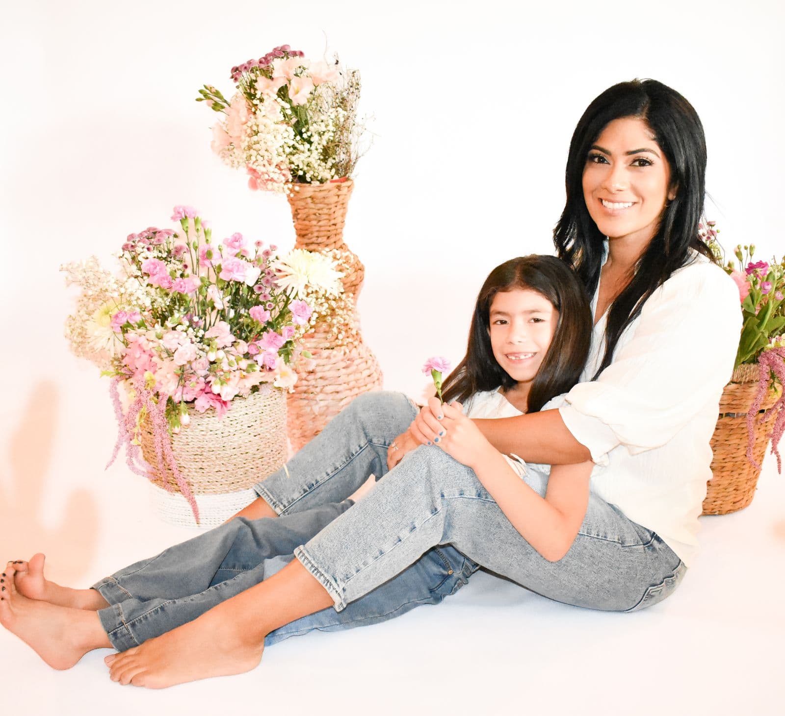 A mother and her daughter seated together beside tall baskets of flowers in a Las Vegas, NV studio