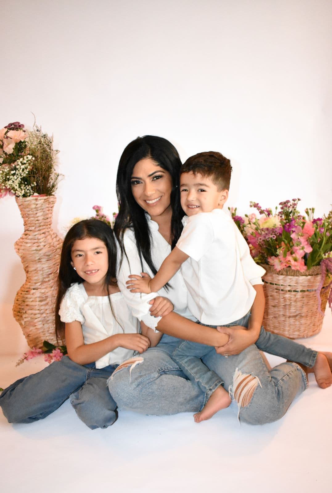 A mother sitting on the studio floor with her two young children among flower baskets, Las Vegas, NV