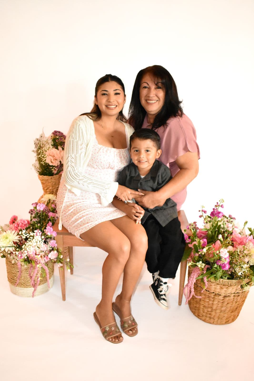Two women seated on a stool with a young boy during a studio family session in Las Vegas, NV